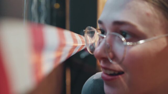 Caucasian woman peeking past caution tape, glasses closeup in dim cafe interior, leaning over redwhite barrier, inquisitive expression, evening bokeh lights and vintage film grain.