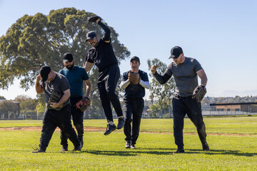 Obraz premium Diverse male teammates in athletic wear and caps walking and leaping across outfield with gloves