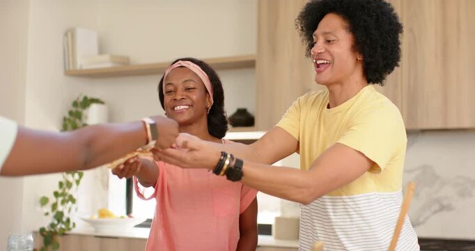 African American couple accepting pizza slice from left person offering, sharing meal at counter