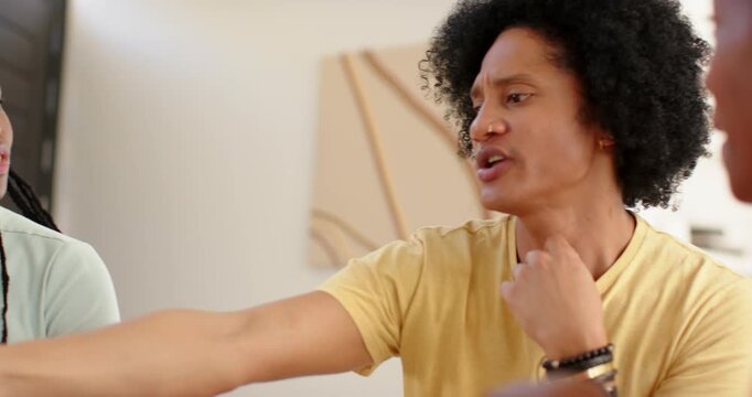 African couple at dining table, woman showing blue phone while man pointing, deciding pizza board