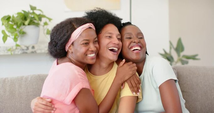 Focus shifting, African American friends hugging closer on sofa, settling into clearer pose