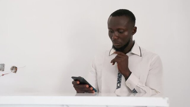 Black man checking phone before date, adjusting collar, rereading confirmation message, tapping screen, pausing to reflect, practicing smile, lastminute reservation check, calm nervous energy, white