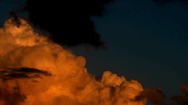 Dramatic sunset clouds with golden light, dark storm clouds at twilight, cinematic orange cumulus cloudscape against deep blue sky
