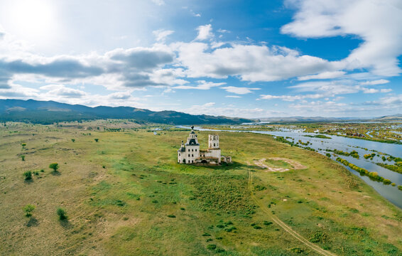 Holy Trinity Church a historic baroque structure overlooks Selenga River near mountains on a cloudy day