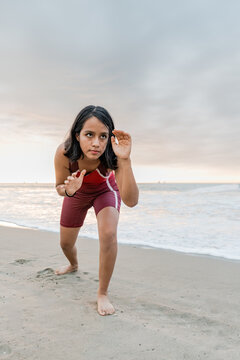 Young athlete of wrestling crouching in ready stance on beach