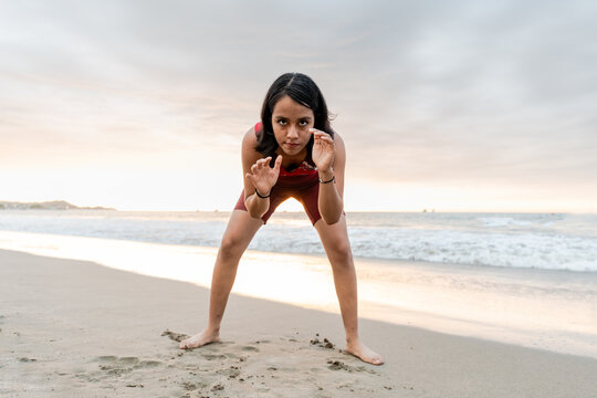 Intense young woman holds a powerful pose on beach