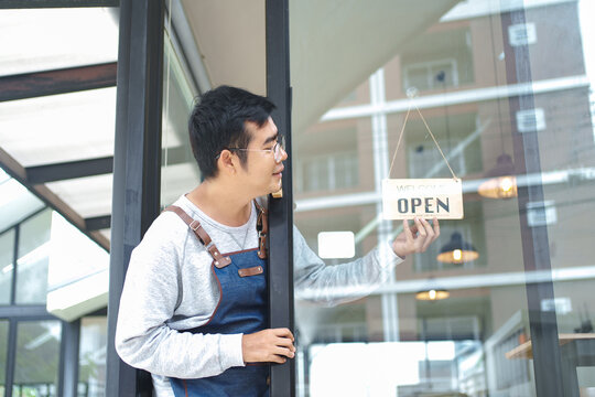 Barista Hanging Open Sign on Cafe Door