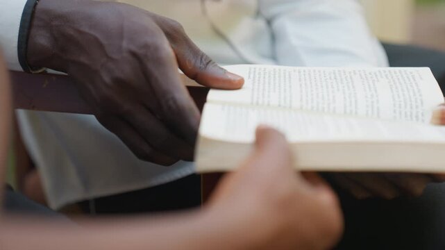 Closeup hands holding open book, romantic date couple sharing pages and poetry, gentle touch guiding page turn, soft natural light, warm tones, calm outdoor vibe, intimate connection and tenderness