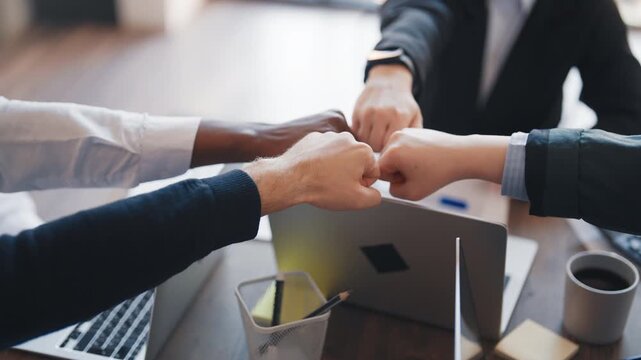 Hands of African, Caucasian, Indian and Asian people in office, teamwork. Colleagues connecting fists, gesture of unity and support, partnership and co-working, make decision in business meeting