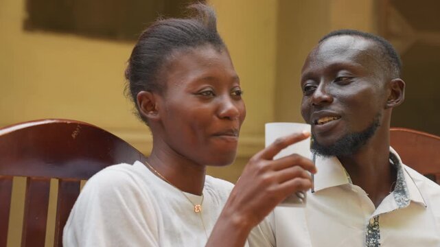 Joyful couple laughter. Smiling pair sharing warm beverages. Couple indulging in cheerful drinks and playful moments. Loving partners exchanging smiles while sharing warming beverages and fun times