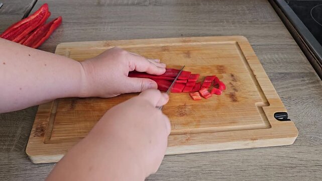 Woman's hands dicing red bell pepper on cutting board