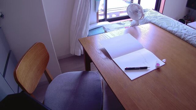 Partially written notebook on a summer day with a cooling fan, quiet everyday moment and signs of daily life for study and lifestyle use