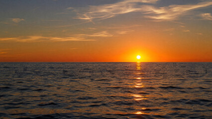 Fototapeta premium Limitless Sea View Beneath Golden Sky. Vast Sea Under Warm Evening Sunlight