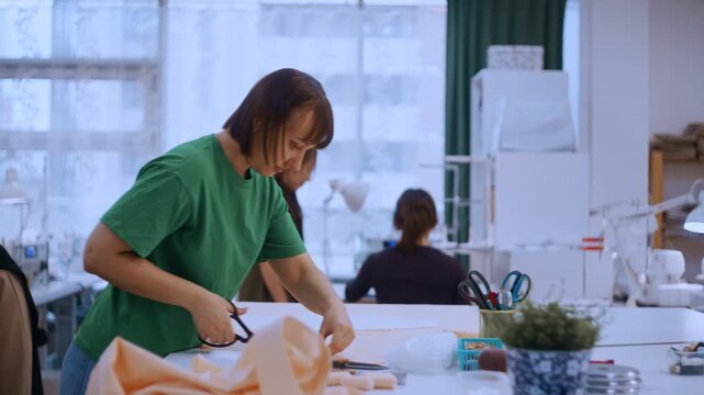 Young woman cutting fabric with scissors during a sewing lesson in a fashion design studio