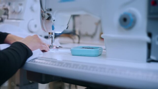 Close up of a woman's hands threading the needle of a sewing machine in a tailor's workshop