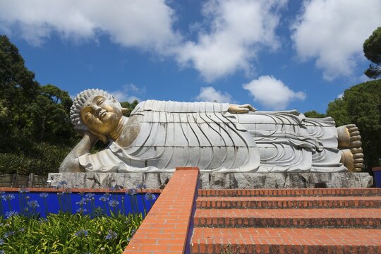 Reclining Buddha statue above an area decorated with flowers and steps in a sunny park, Bacalh&ocirc;a, Bacalhoa Buddha Eden, Quinta dos Loridos, largest oriental garden in Europe, Bombarral, Oeste, Centro, Portugal