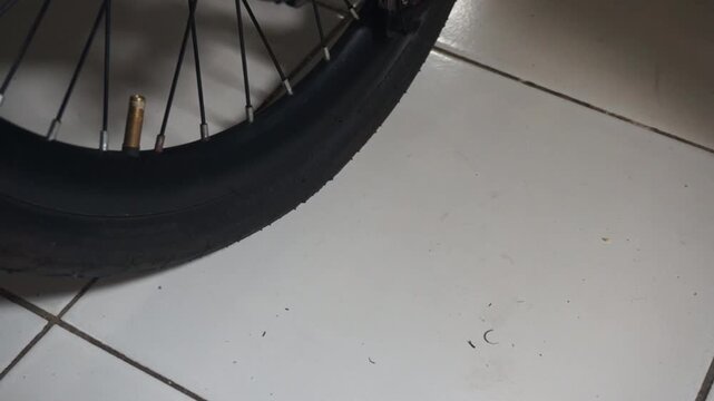 A close-up video of a man's hand using a black hand pump to inflate a flat bicycle tire, demonstrating repair and self-reliance in the outdoors.