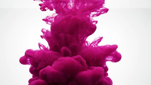 Mesmerizing shot of vibrant fuchsia ink spreading and dissolving in water against a bright white background