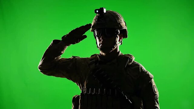 Silhouette of a Brave Soldier Saluting in Full Military Uniform and Tactical Gear Against a Green Screen Background