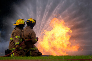 Naklejka premium Firefighters bravely battle intense flames with water spray during training exercise