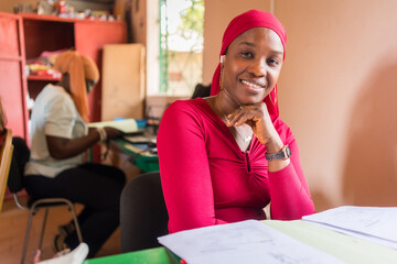 Portrait of smiling young african business woman sitting at desk in office working on laptop, enterpreneurship in africa © davide bonaldo