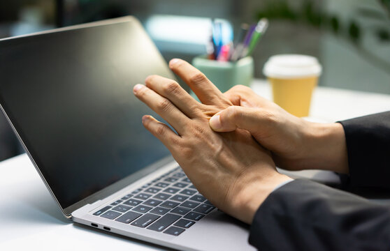 Businessman experiences pain on the back of his hand when pressing it with his fingers this relates to concepts of arthritis, trigger finger and hand health diagnosis.