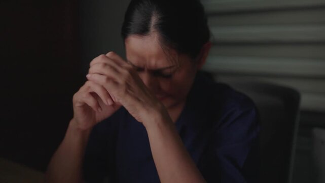 Despair in Solitude: A woman clutches her head, her face etched with distress and anguish, reflecting a moment of profound sadness or worry.