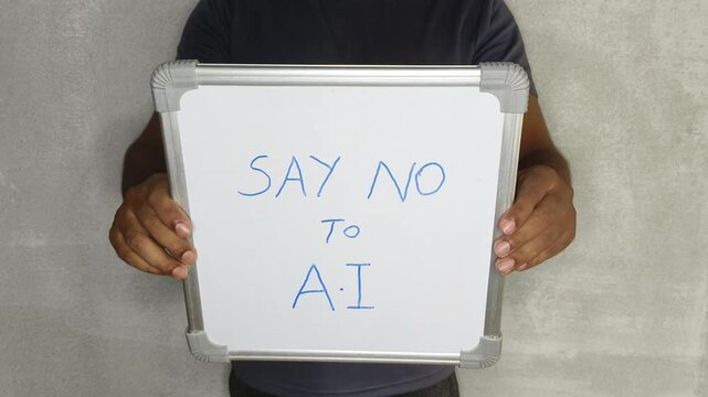 Hands of adult activist person holding whiteboard with "say no to AI" warning text message. Unemployed virtual work from home worker or employee protest against artificial intelligence after job loss.