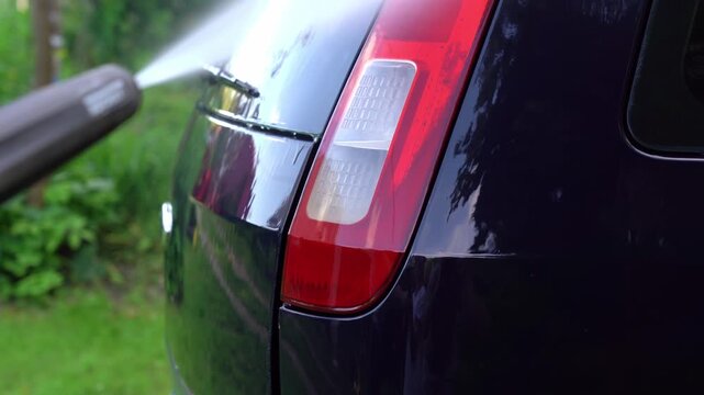 Close up of washing car headlight with pressure washer outdoors. High pressure car wash. Car wash
