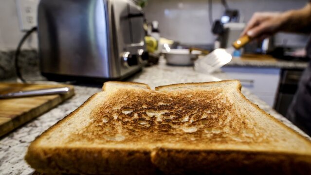 Man buttering toast in kitchen setting.