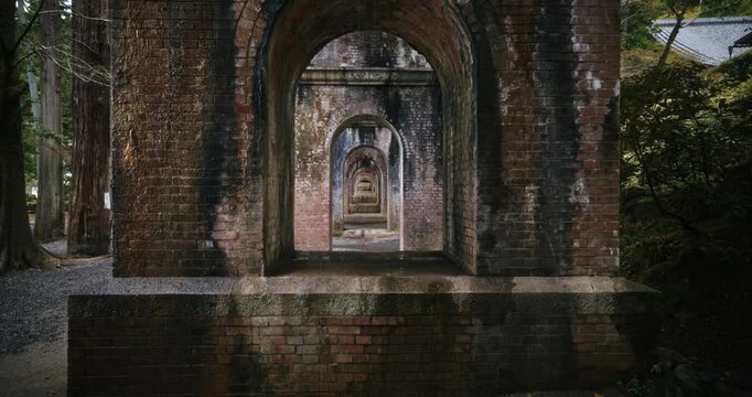 Slow dolly in on old brick arches under Japanese bridge