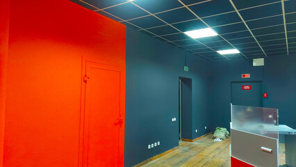 Work is in progress in a room with orange and gray walls and new lighting setup in a commercial space © Сергей Семенов
