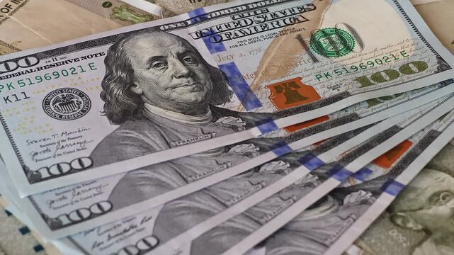 100 american dollar banknotes (USD) are placed on top of Indian rupees (INR). A hand places currency over scattered 500 bills. Concept of exchange rate, global finance, and international economy.