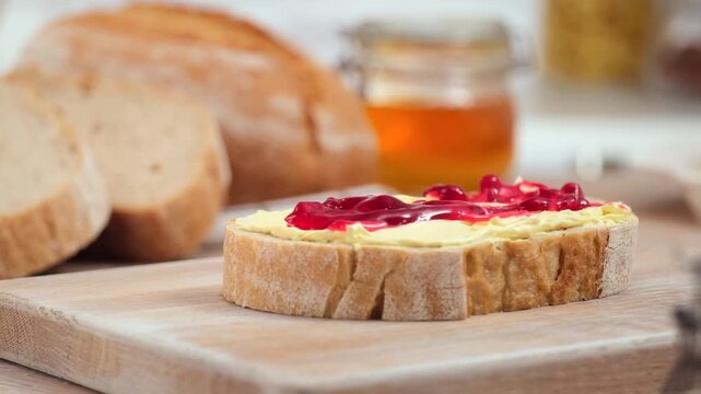 Butter and jam spreading on fresh bread slice close up homemade breakfast, copy space