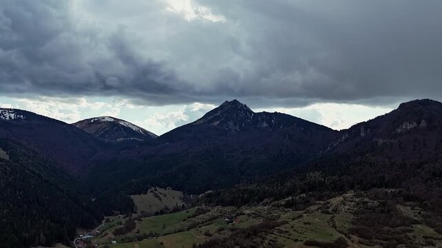  Aerial Hyperlapse Flying Sideways Revealing Rocky Mountain Peak Under Dramatic Overcast Sky in April