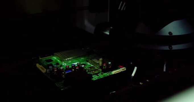 Сlose-up footage of a  motherboard transitioning along a conveyor system.Bright, pulsing automated quality control lights flash, scanning the microelectronics.
