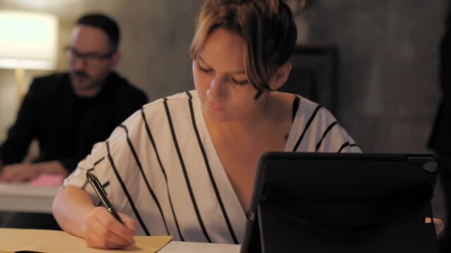 Businesswoman writing notes at her desk
