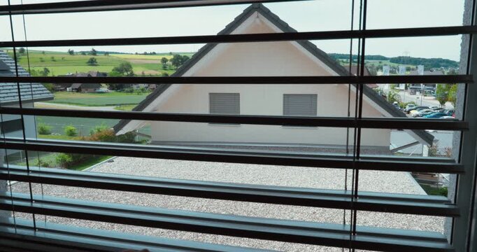 Hand lowering an insect screen on a window to keep insects outside while allowing fresh air into the home. Concept of home comfort, ventilation, pest protection, and residential living.