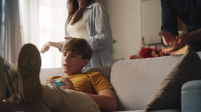 Parents scolding naughty teen son for video game addiction, taking joystick away