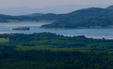 Fototapeta premium Stunning aerial view of Lake Plastira in Greece surrounded by lush green forests and rolling hills. Beautiful natural reservoir landscape, perfect for travel and nature concepts.