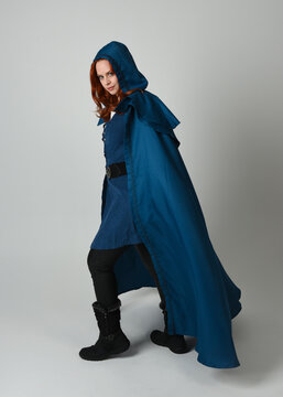 full length portrait of model wearing medieval fantasy warrior historical costume with blue hooded cloak. silhouette figure,  walking away in back view on studio background.