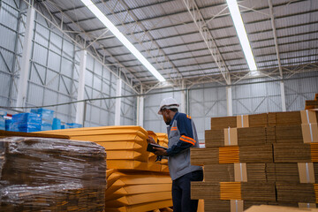Fototapeta premium Black Factory Worker Using Digital Tablet in Cardboard Warehouse