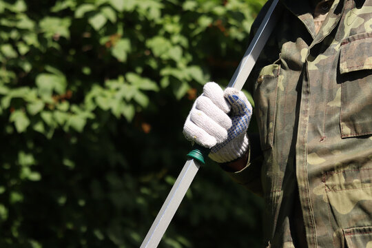 Garden pruner (long-handled pruner), in the hands of a gardener close-up. The tool is designed for pruning high branches and wilted shoots. Hands in gloves with telescopic garden pruners