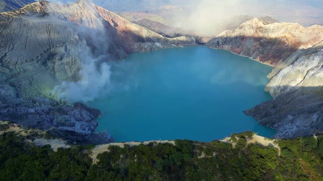 Cinematic aerial view of Mount Ijen volcano at sunrise &ndash; Breathtaking drone shot of the toxic turquoise crater lake and sulfur smoke clouds in East Java, Indonesia mountain landscape 4k