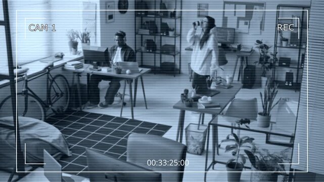 Wide CCTV shot filmed by overhead security camera of two diverse web developers working on projects on computers in cozy tech startup office, walking to get coffee and discuss tasks