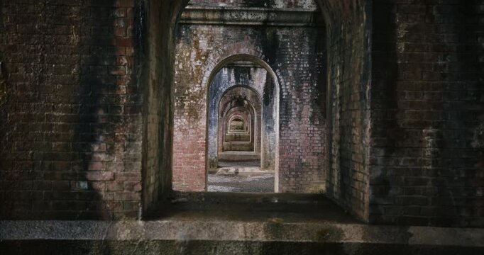 Dolly in on old brick archways under Japanese bridge