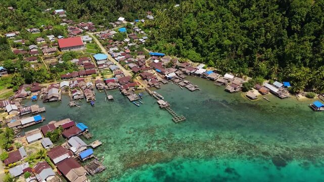 Breathtaking high angle split view of lush palm jungle and vibrant ocean reef &ndash; Majestic untouched shoreline of Banggai Sulawesi, clean cinematic background asset for commercial tourism