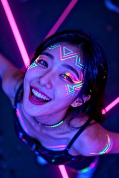 Joyful young South Korean woman with glowing neon uv face paint in creative blacklight festival portrait.