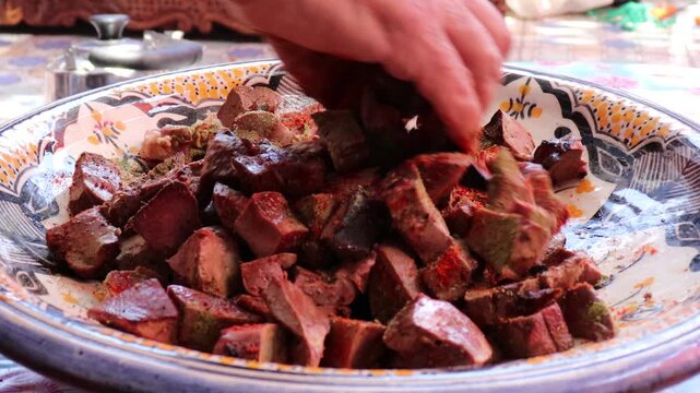 Seasoning lamb liver with spices for Moroccan boulfaf in pottery