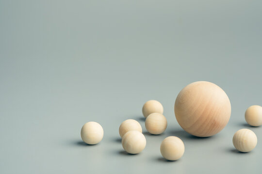 Wooden spheres of different sizes arranged together with one larger sphere at center, representing influence, leadership, coexistence, hierarchy, support, central role and power dynamics 